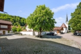 Hof mit Brunnen und Blick auf Kirche und Kaffee - „Attraktive 2-Zimmer-Wohnung mit Balkon in Hammer bei Siegsdorf, zu verkaufen“